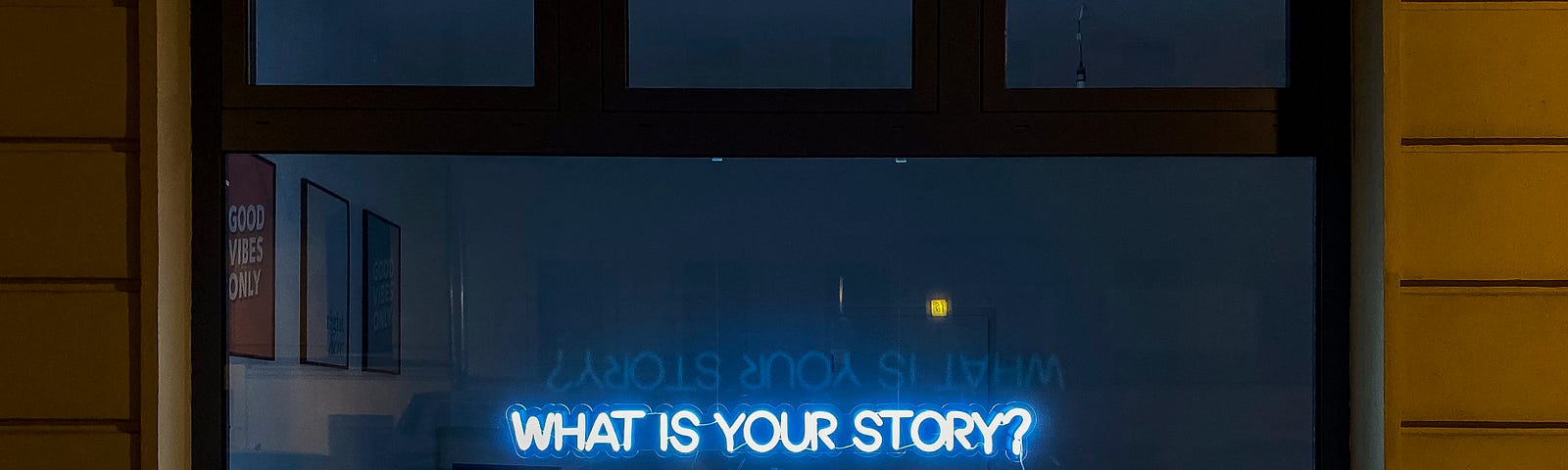 A window with a neon sign saying ‘what is your story’