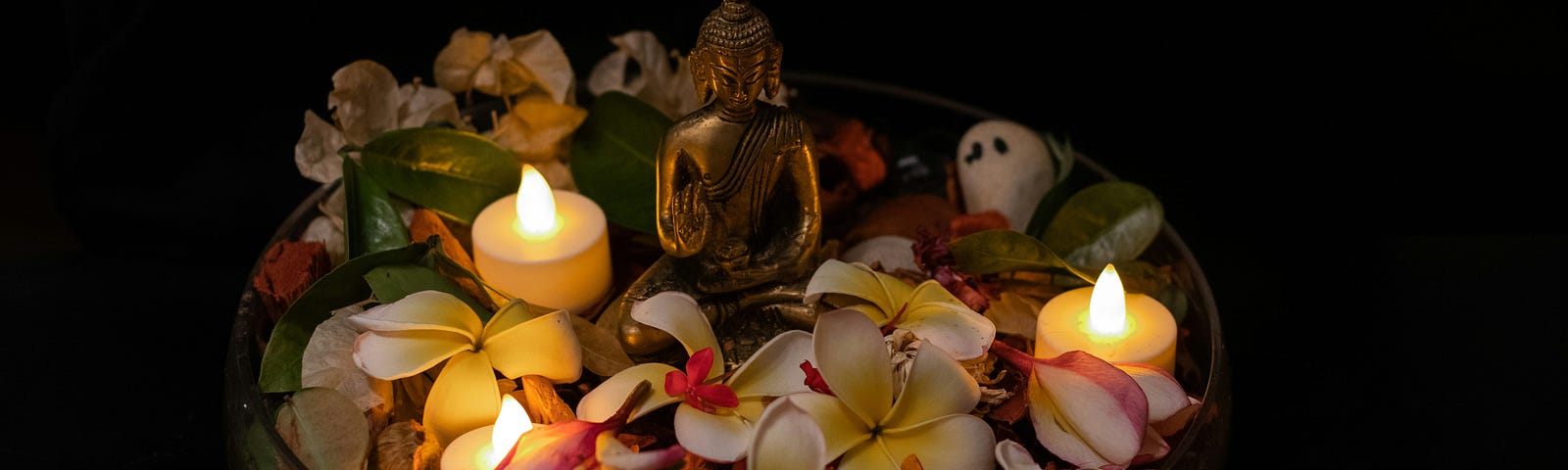 An idol surrounded by flowers and candles