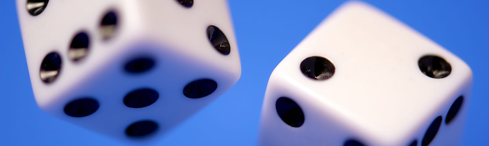 A standard set of dice midroll against a blue background.