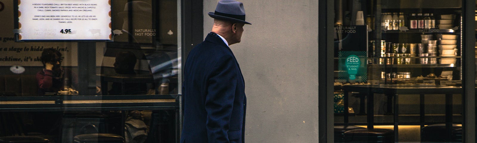 Picture of a spy with a briefcase walking past a bookshop via Alt text on Medium