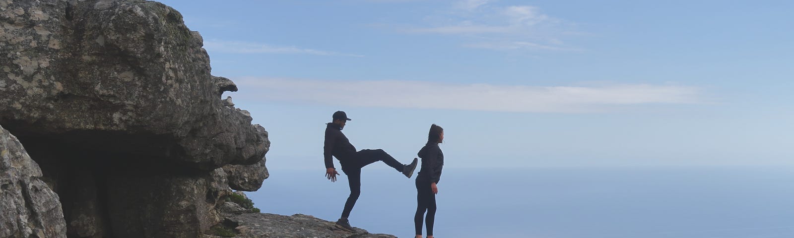 Man ready (pretending) to kick a woman off a cliff