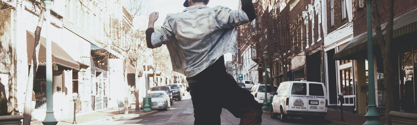 A man jumping for joy in the middle of the street.