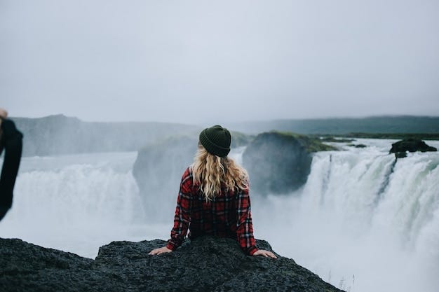 Young woman sitting at the edge of a cliff looking at waterfalls
