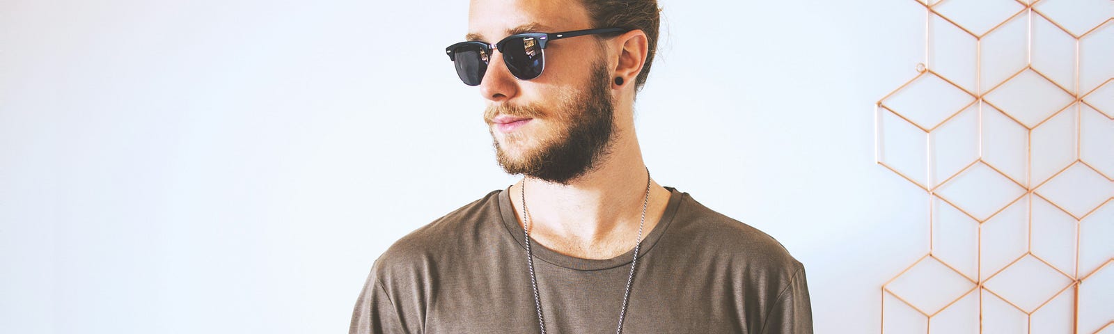 A man with a beard, sunglasses, and manbun.