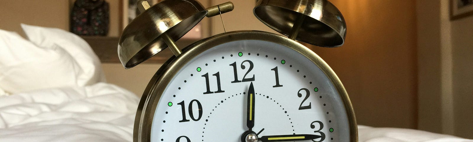 An old-fashioned analogue alarm clock in close-up on top of a bed, emphasising the importance of being punctual for work.