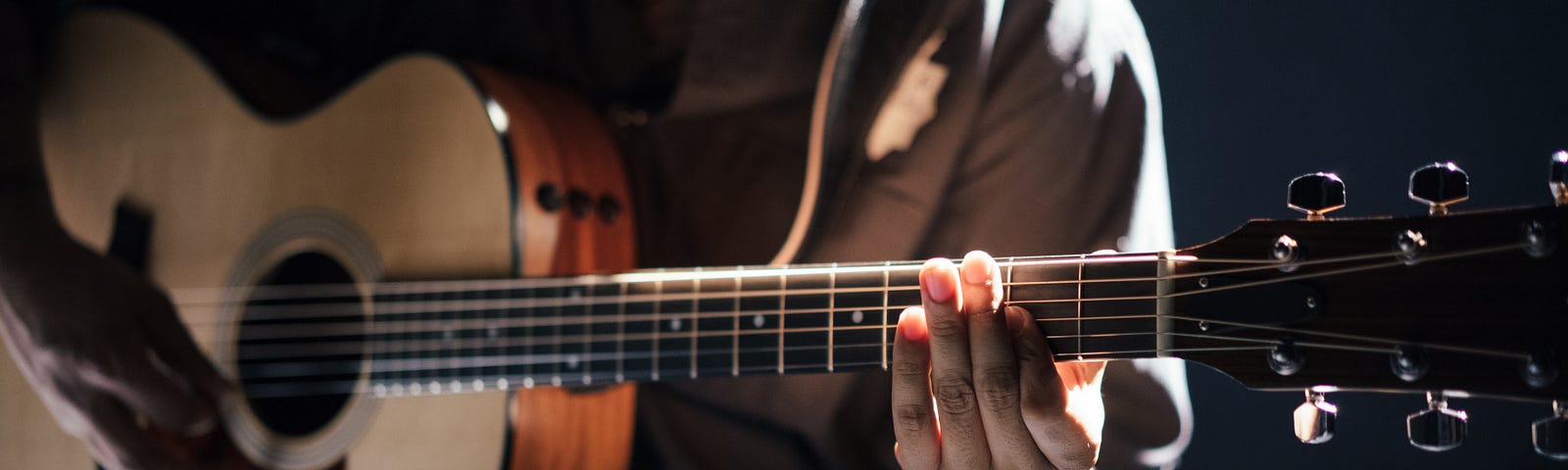 A man strums a guitar under nice lighting.