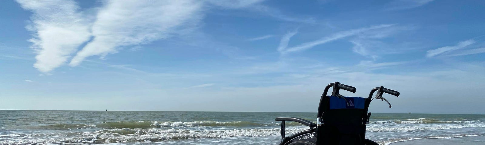 empty wheelchair on the shore facing the ocean