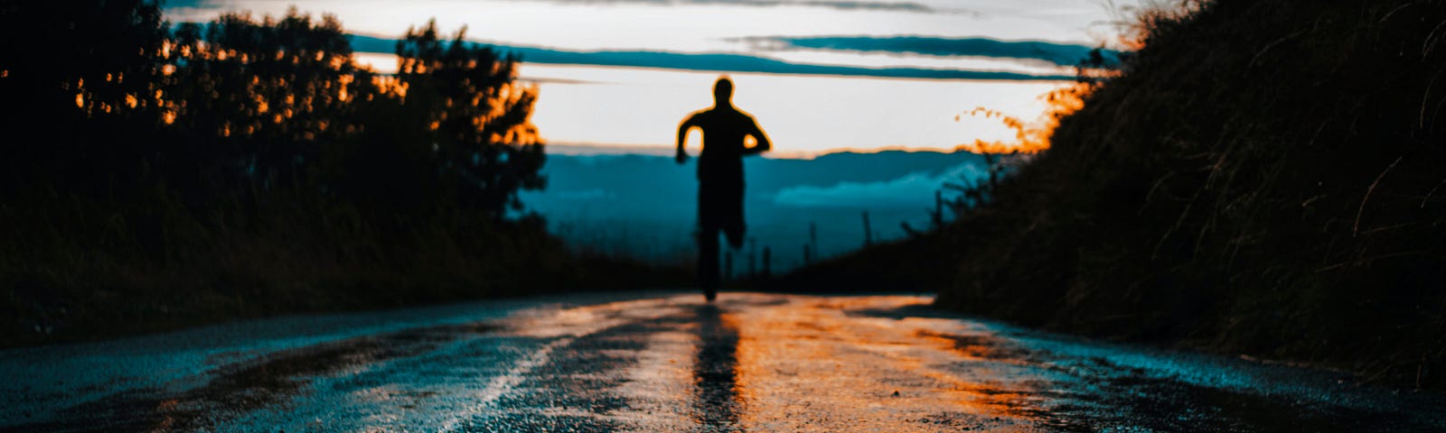 Man, seen as a silhouette, running at dawn.