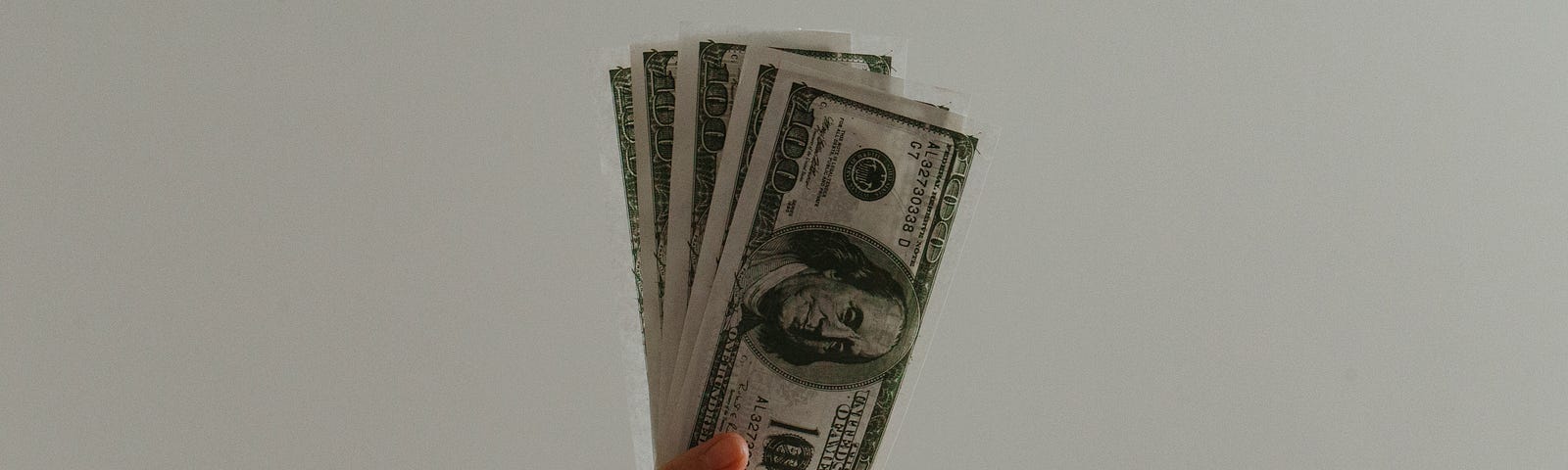 A hand holding cash in front of a white background.