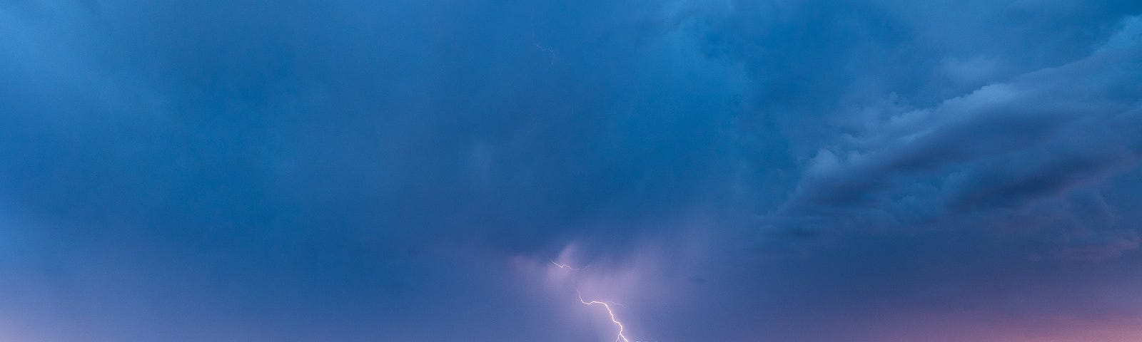 lightning strike and pending rain storm in shades of lavender and blue