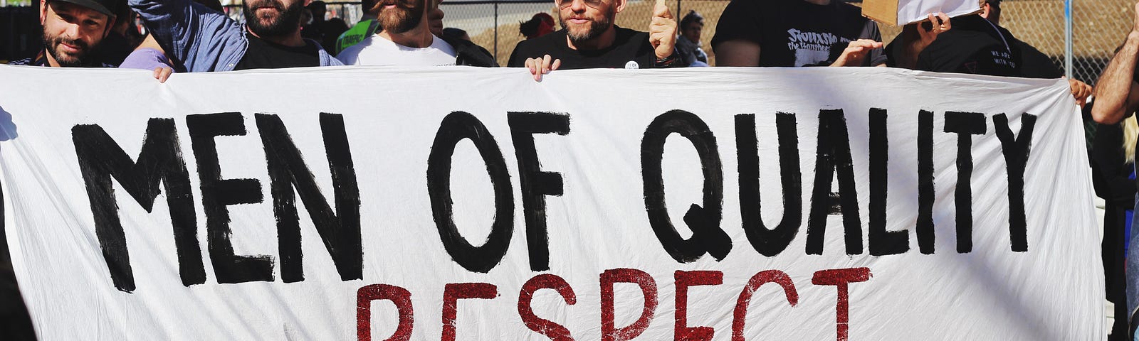 A group of men holding a banner proclaiming “Men of Quality Respect Women’s Equality”. Lashing back against the overturning of Roe vs Wade in the United States, and marching in favor of women’s rights.