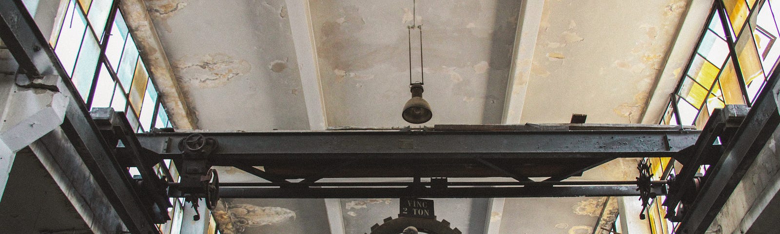 A sculpture of a man pushing a large gear near the ceiling of a building.