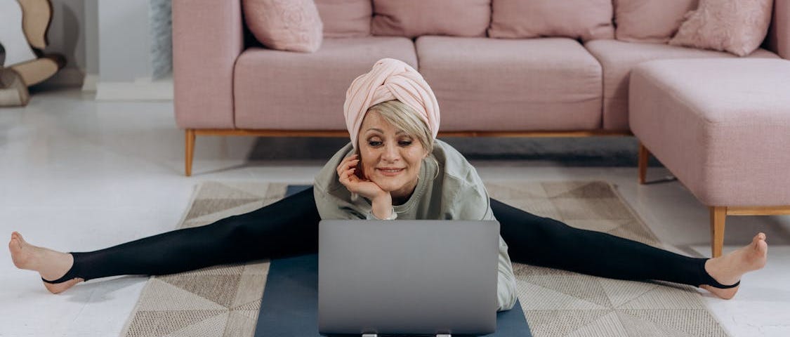 Older woman in headwrap exercising with laptop.