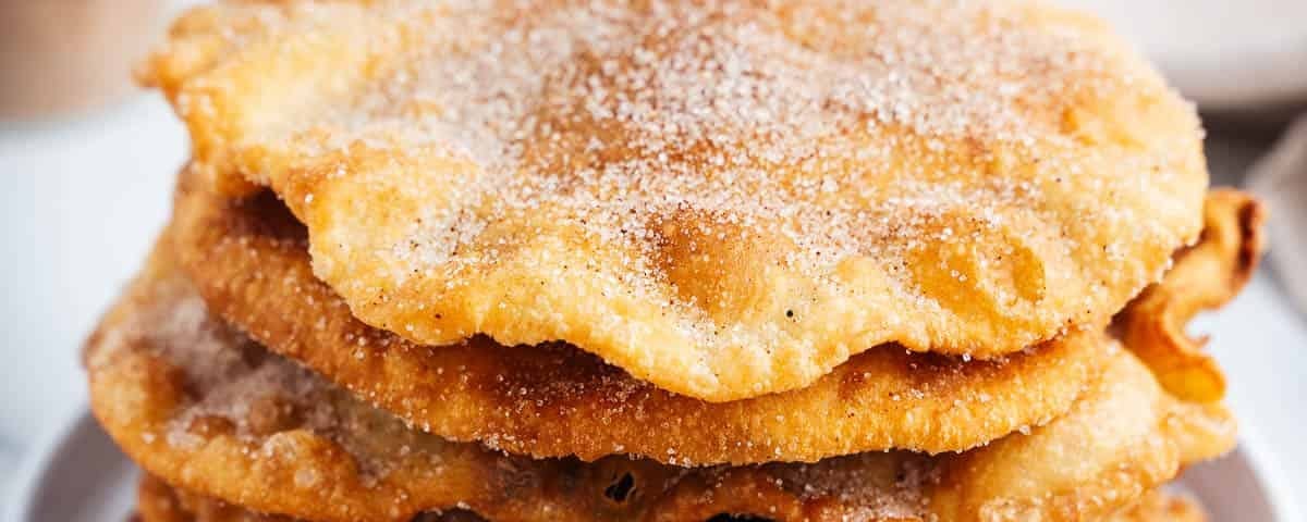 Bunuelos stacked on a white plate