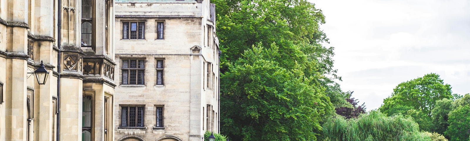 A student with a backpack walks past an old university building.