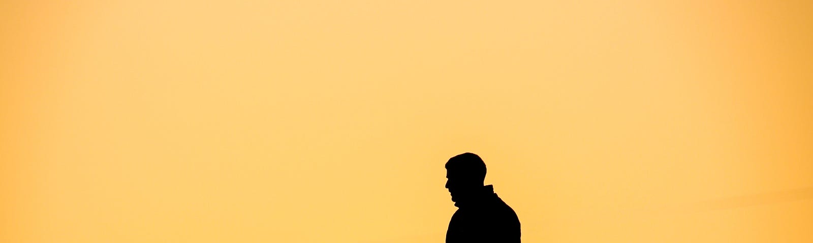 Man walks down relatively straight hill (at about 20 degrees) hill, traversing right to left. Yellow background.