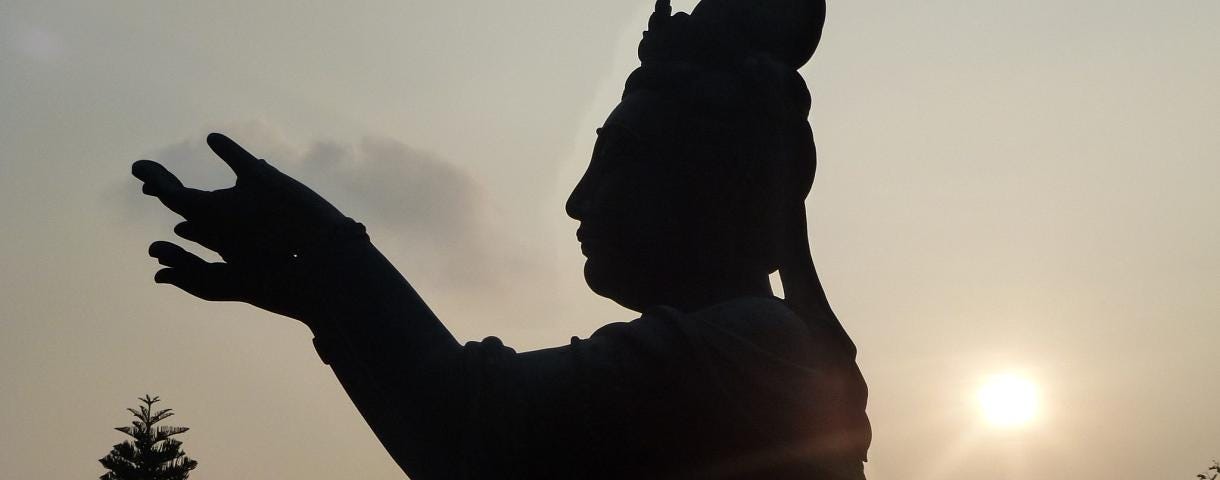 A statue with hands raised, sun rising in the background