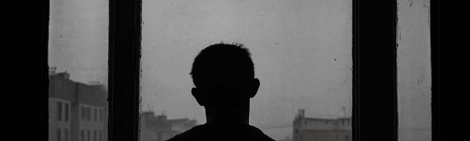 a man staring out of the window into a gloomy, rainy day