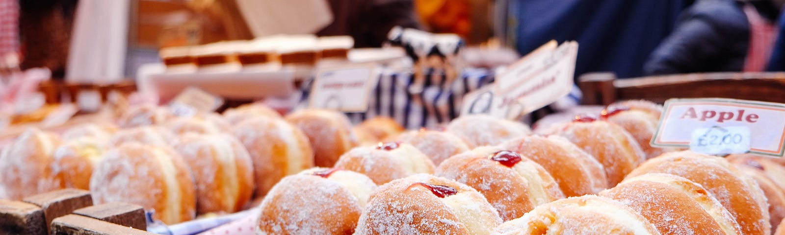 A display of fresh powdered jelly doughnuts sits in a bakery.