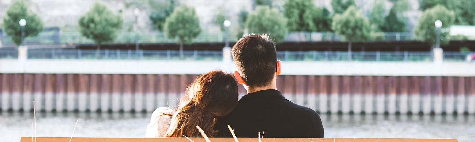 a couple sitting together on a wooden bench outside