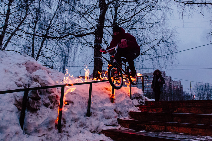 Cyclist freestyling on an outdoor handrail set aflame