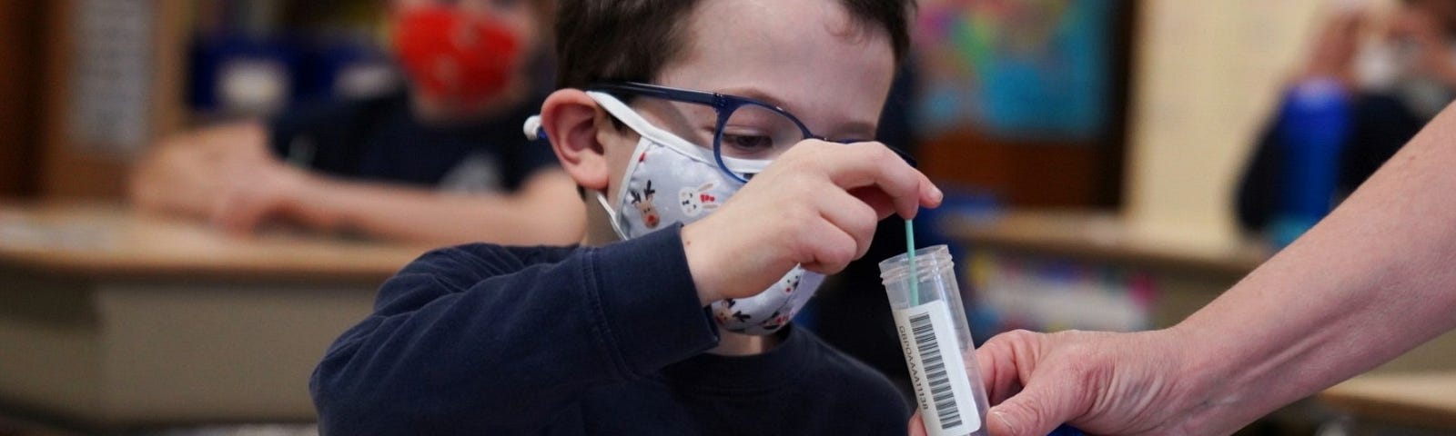 A child places his test swab in a vial at South Boston Catholic Academy in Boston, Massachusetts, January 28, 2021. Photo by Allison Dinner/Reuters