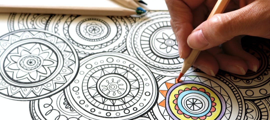 Someone coloring in an illustration on paper