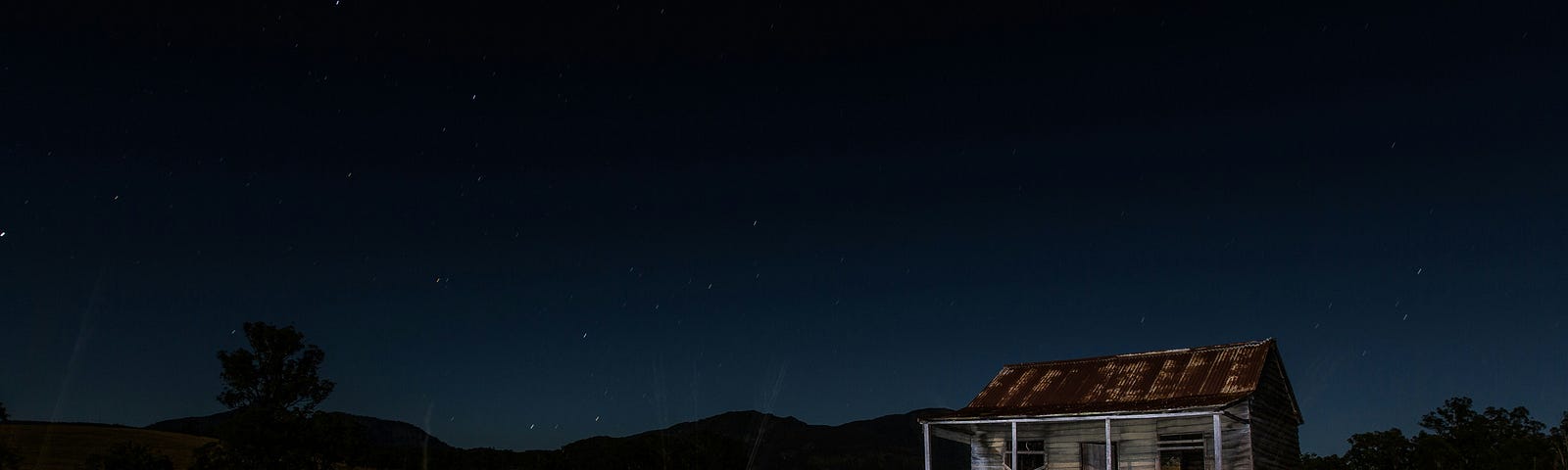 A picture of a shack on a prairie at nightfall.