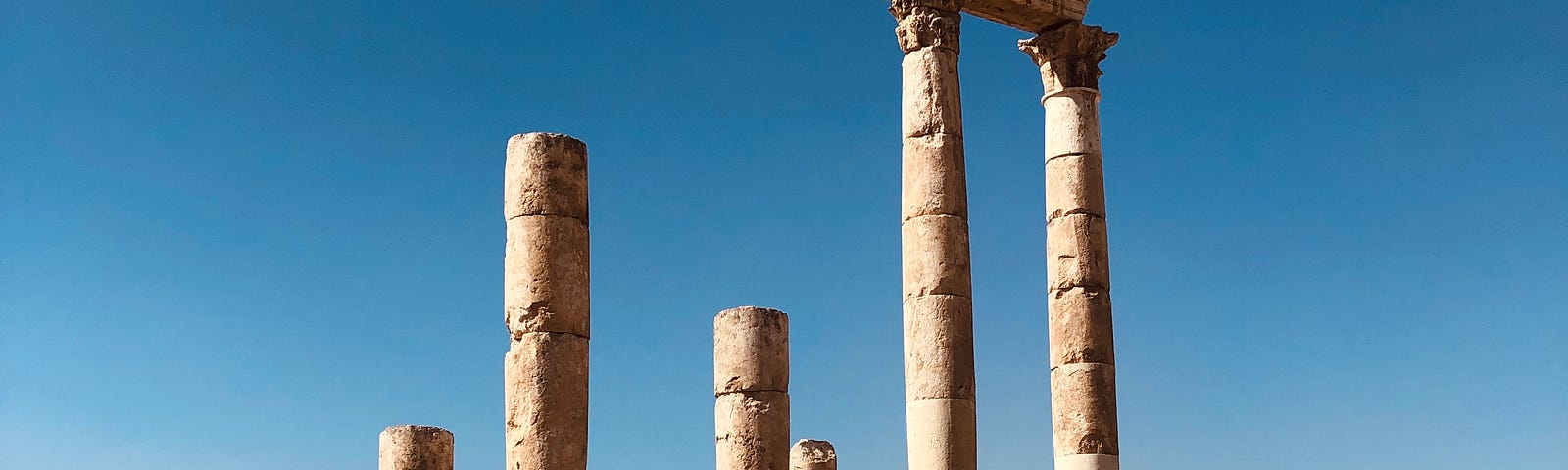 Ruins in a dry sandy place, with pillars standing and others collapsed