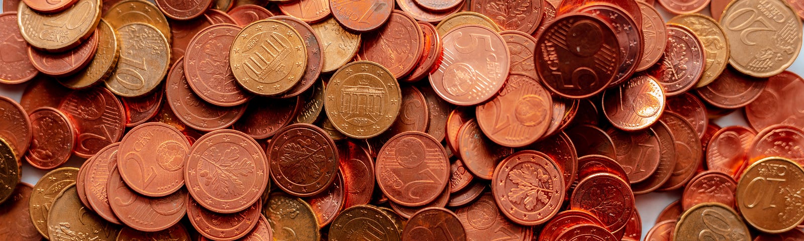 A pile of shiny coins is spread across a table