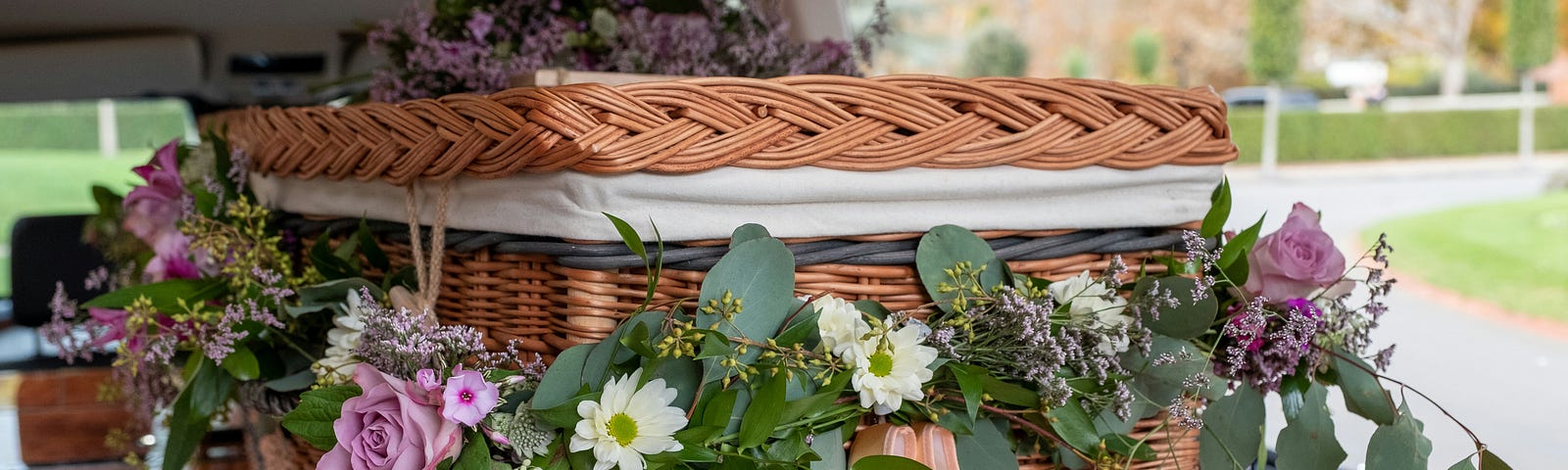 A wooden coffin with flower arrangements around the coffin.