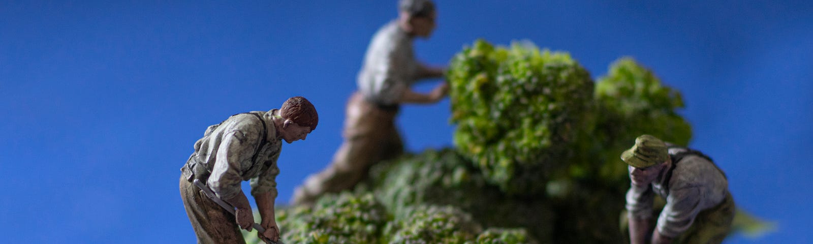 A stalk of broccoli with plastic men digging and mining it.