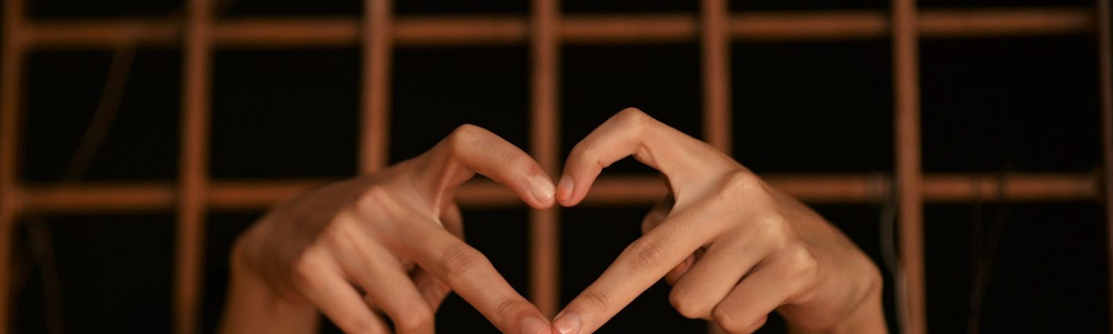 A person behind bars forming a heart with their fingers