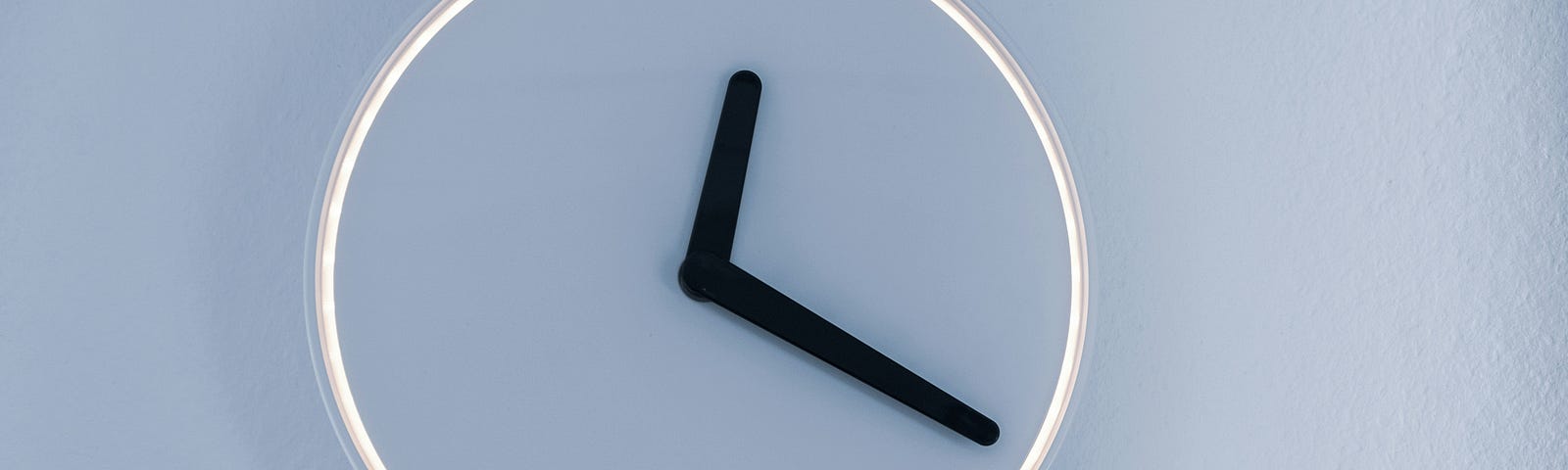 A modern clock with a white light on its edge
