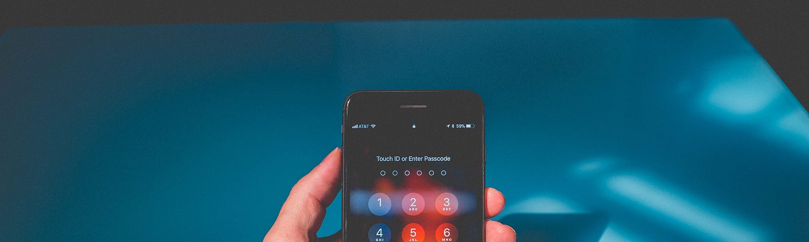 A hand holding a locked phone against a blue background