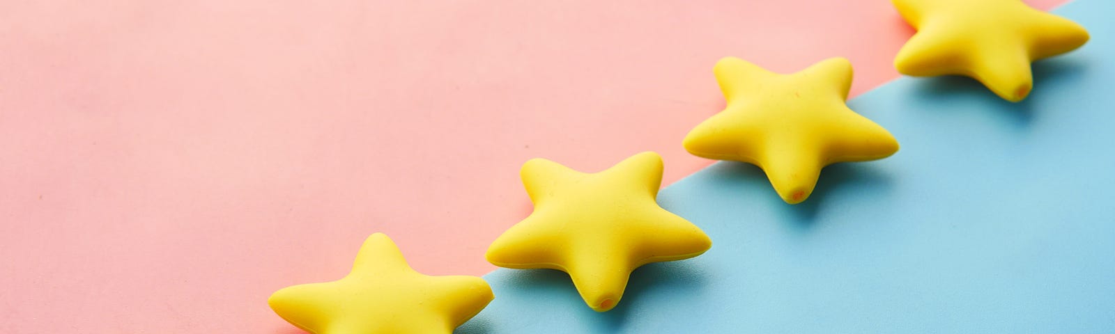 five star crackers lined up in a diagonal row; one side is baby pink and the other side is baby blue. The crackers themselves are yellow