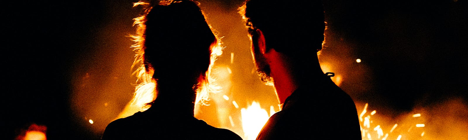 A man and woman looking toward a bonfire and another couple