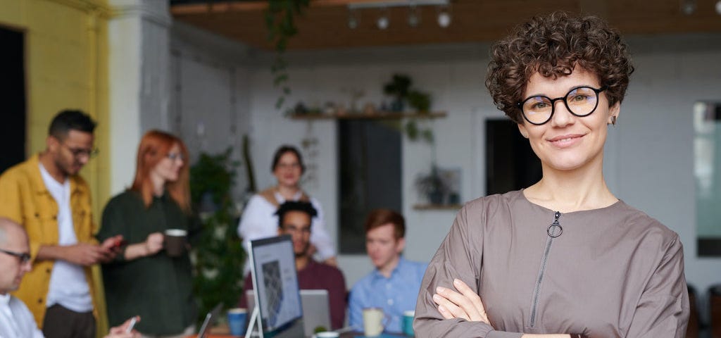 A picture of a lady with her colleagues in the background.