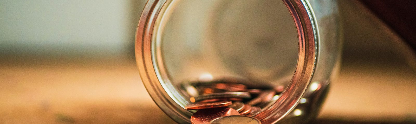 A jar of coins spilt on a table.