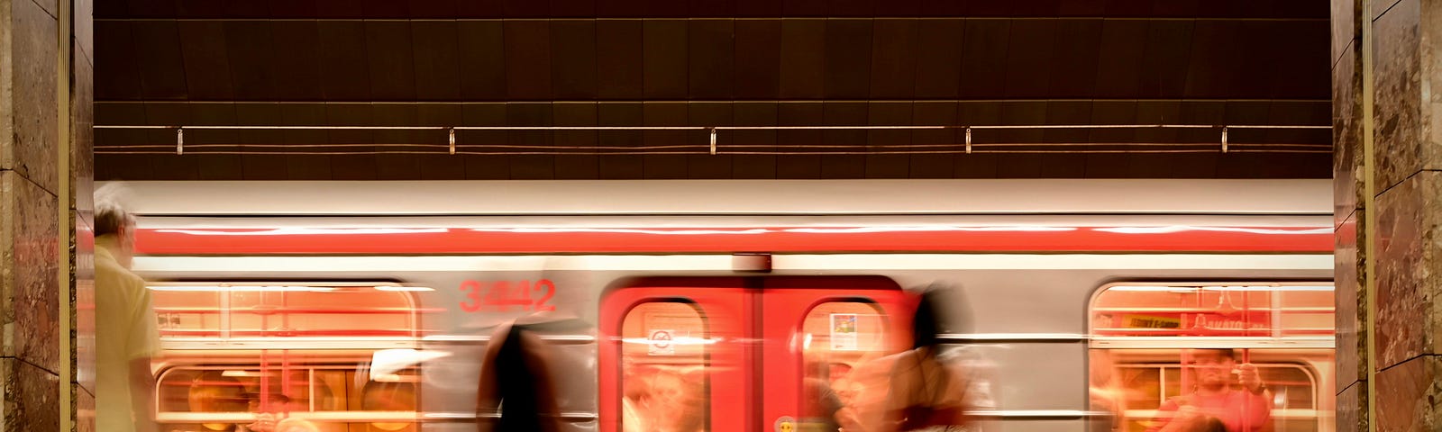 A metro train speeding past people waiting on the subway platform.