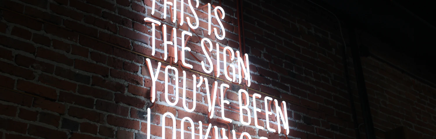 Neon sign on a wall saying “This is the sign you’ve been looking for”