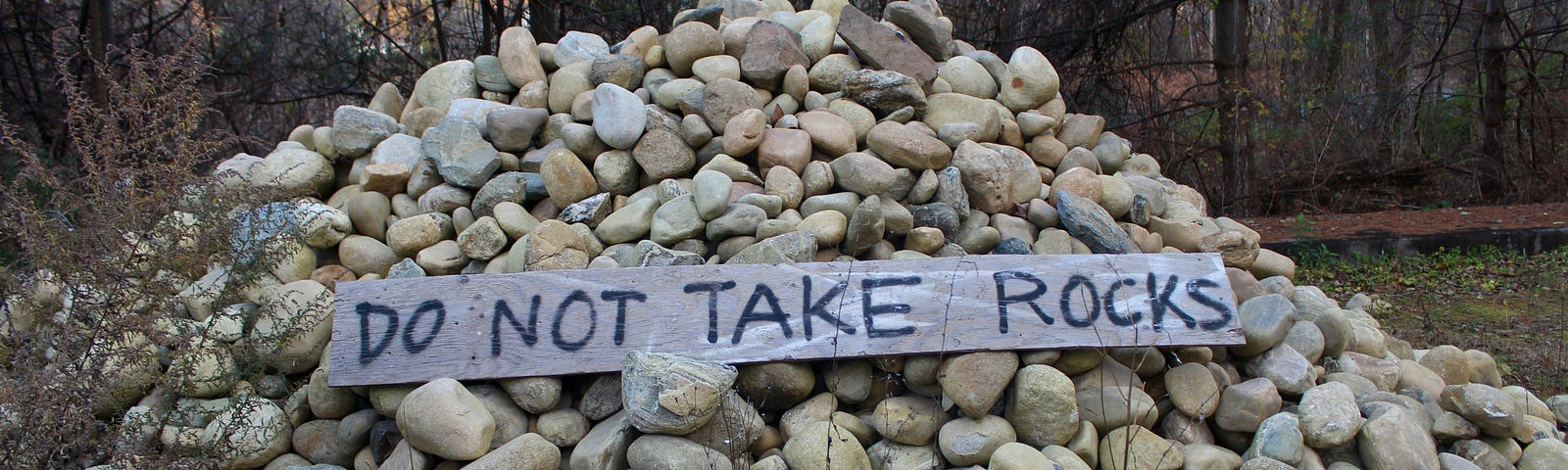 pile of rocks with sign reading do not take rocks