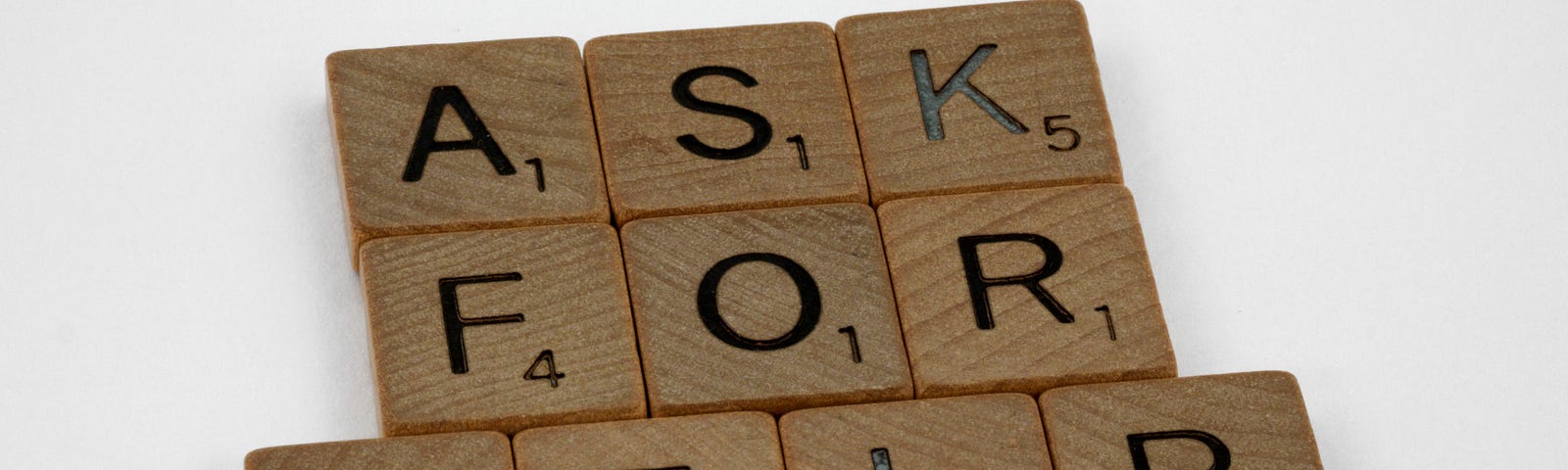“ASK FOR HELP” written with Scrabble tiles