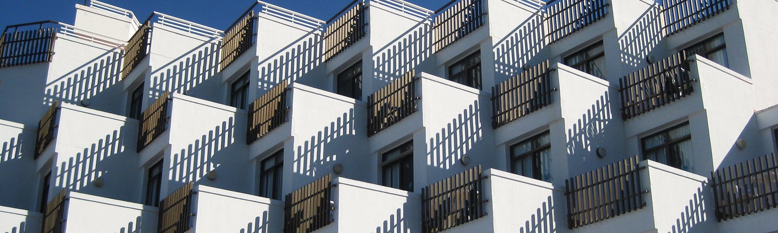 A group of similar-looking white condos against a cloudless blue sky represents how repurposing content can be helpful for creators.