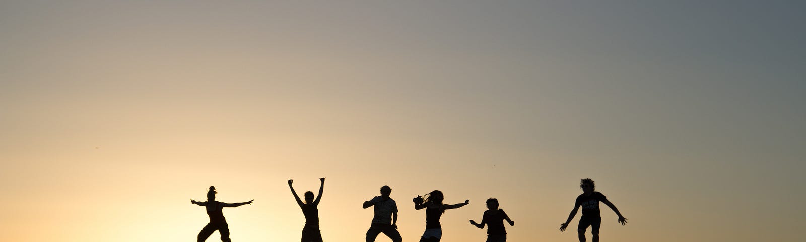 Six young adults (in silhouette) jump into the air, with sun setting behind. Physical activity is associated with a lower risk of dementia.