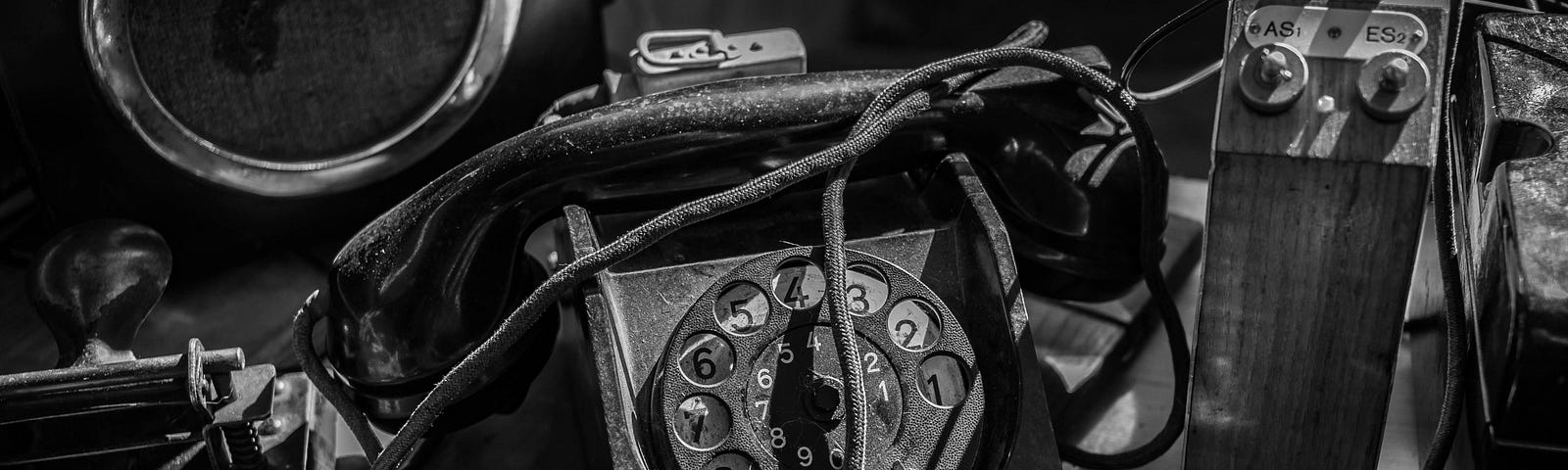 An antiquated phone with and assortment of tools and wires.