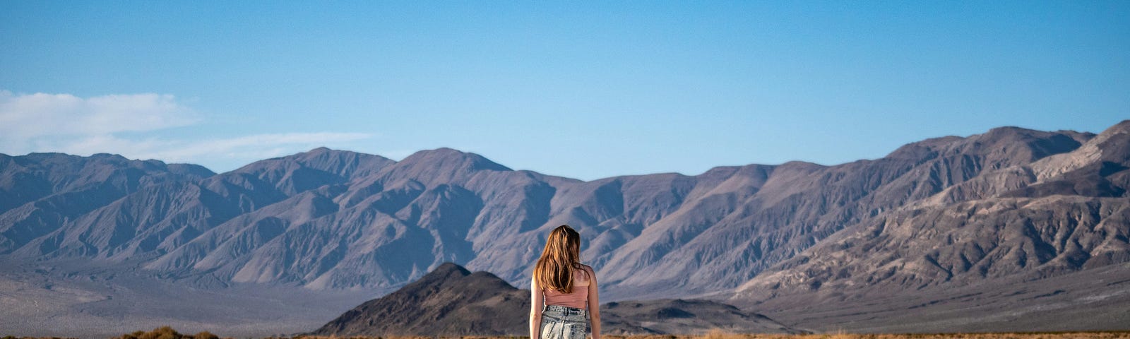 A girl walking away from the viewer in a desert