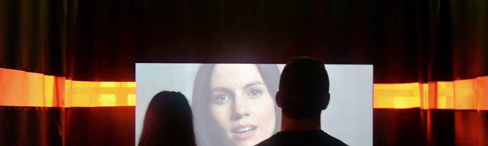 Two people watch a face on a screen