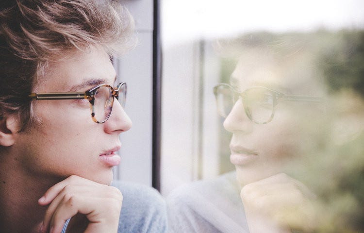 man in glasses looking out window