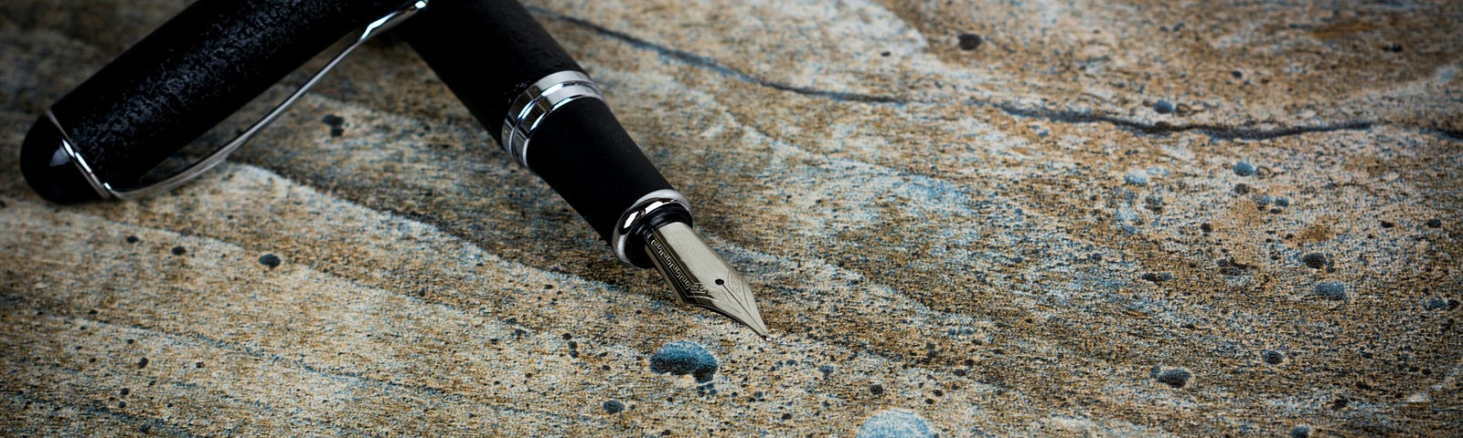 Fountain pen on rough wooden surface, with the nib uncapped for writing.